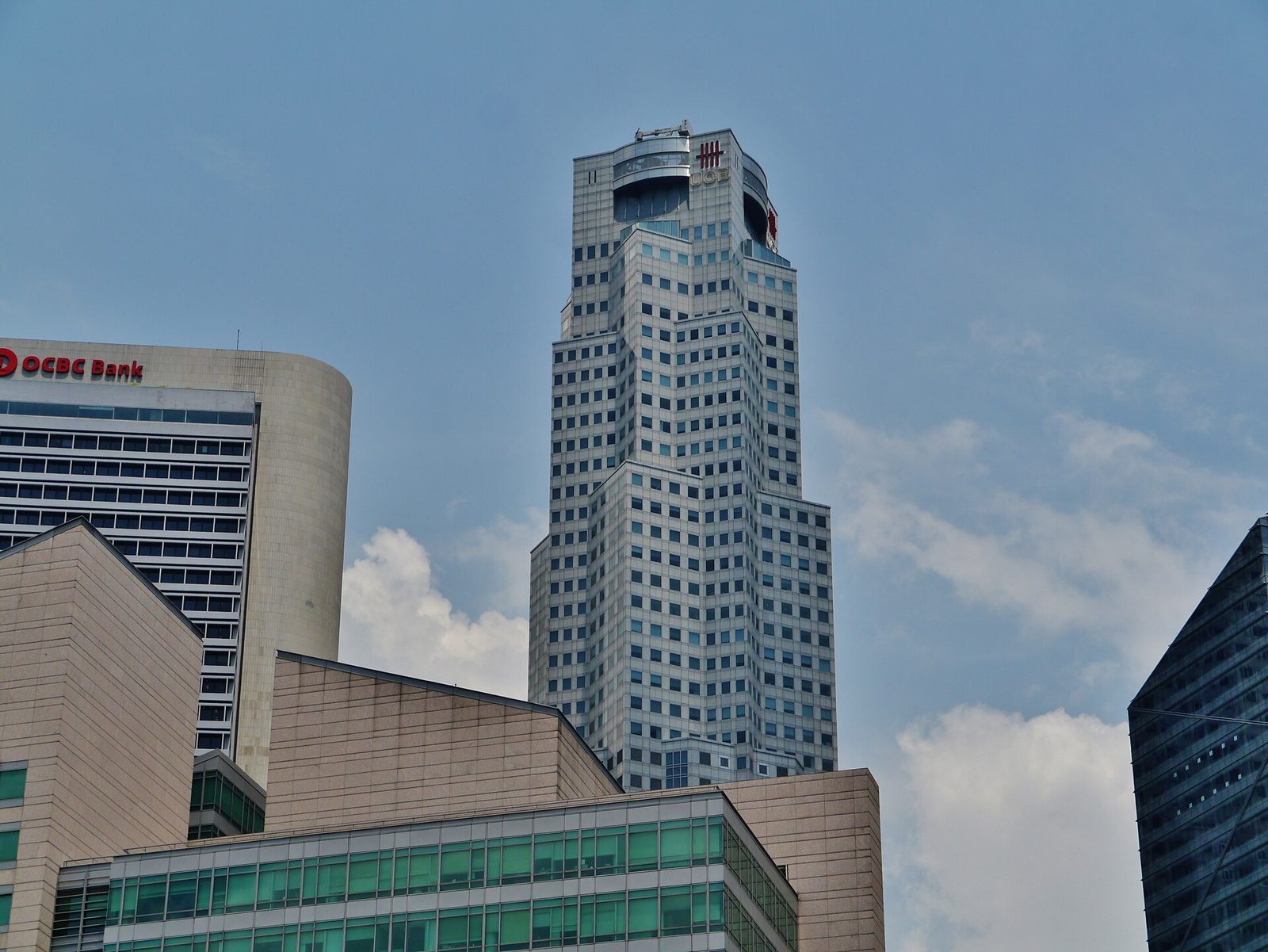 La tour UOB Plaza et son logo UOB au sommet, à côté d'un immeuble portant l'enseigne OCBC Bank, sous un ciel bleu