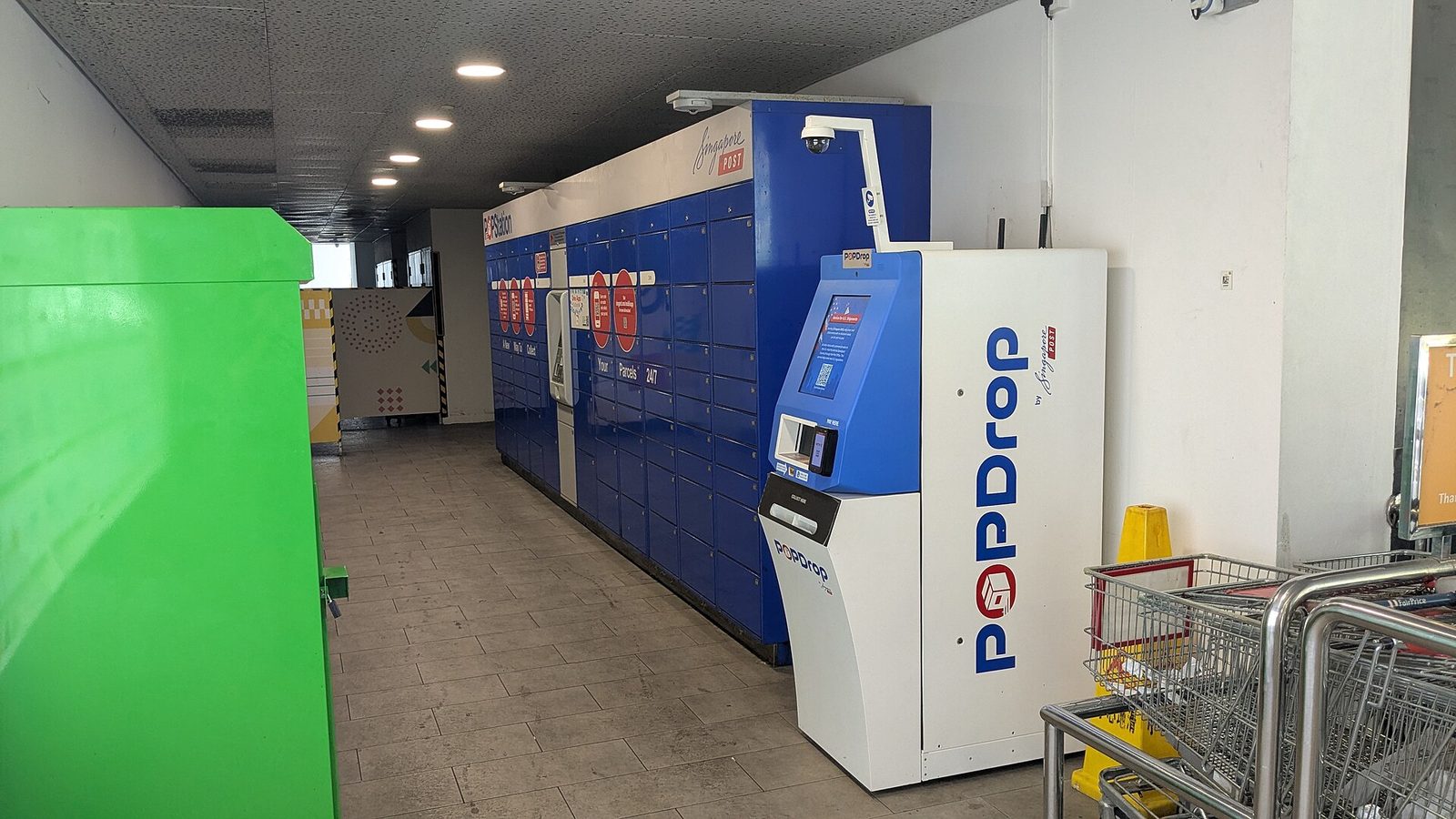 Une rangée de casiers à colis bleus POPStation et une borne POPDrop de SingPost dans un centre commercial