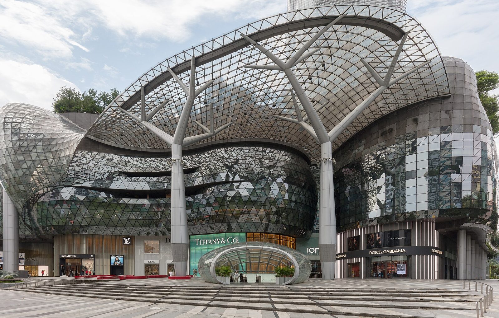 L'entrée principale d'ION Orchard sous sa grande verrière en forme de vague soutenue par des piliers d'acier ramifiés