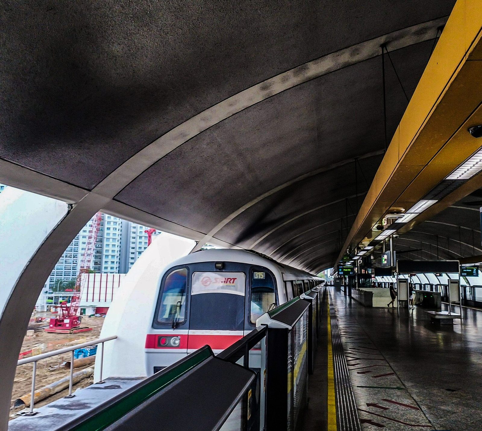 Une rame blanche et rouge du MRT arrivant le long du quai d'une station aérienne couverte