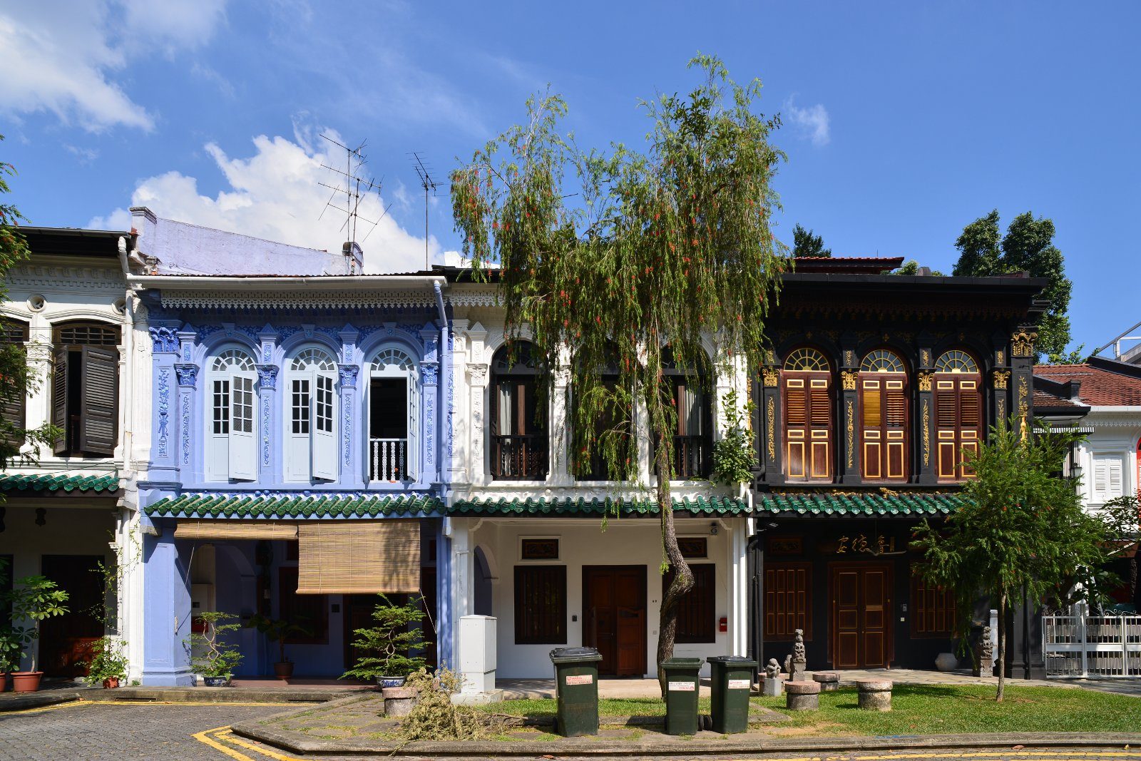 Rangée de maisons mitoyennes anciennes à deux étages, aux façades bleue, blanche et brun foncé ornées de volets en bois, sur Emerald Hill Road