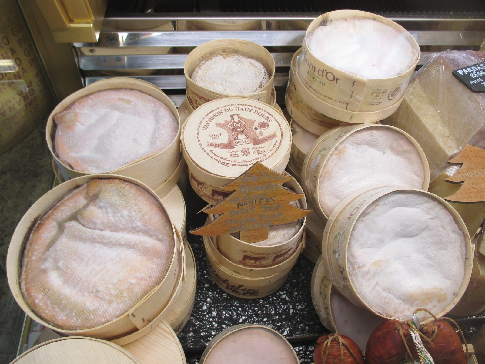 Des fromages Mont d'Or et vacherins du Haut-Doubs dans leurs boîtes en épicéa, sur l'étal d'un fromager