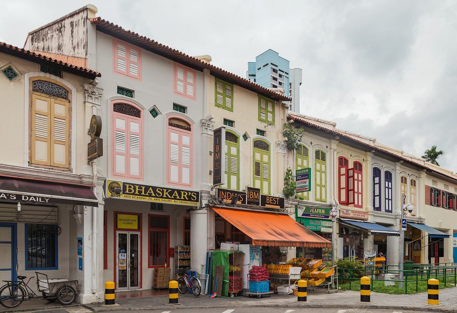 Shophouses aux volets colorés de Kerbau Road, à Little India, avec des boutiques et un étal de fruits sous un auvent orange