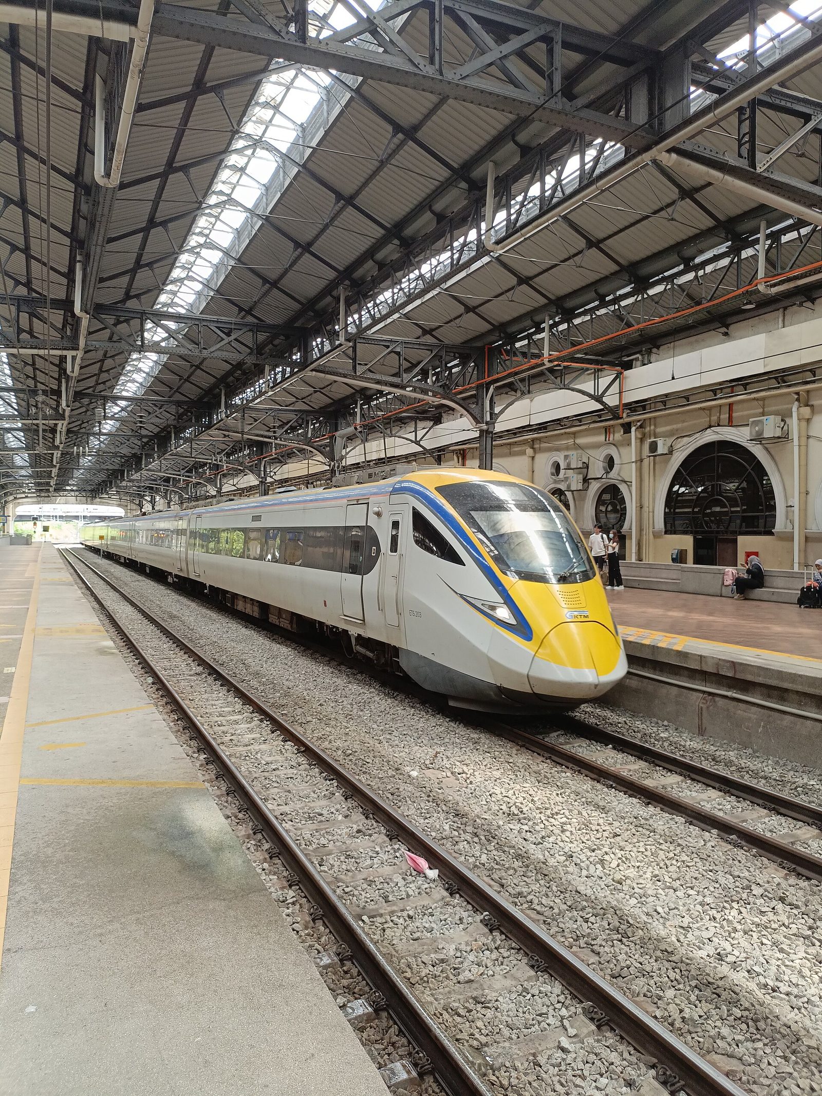 Un train ETS blanc et jaune de la compagnie KTM à quai sous la verrière de l'ancienne gare de Kuala Lumpur