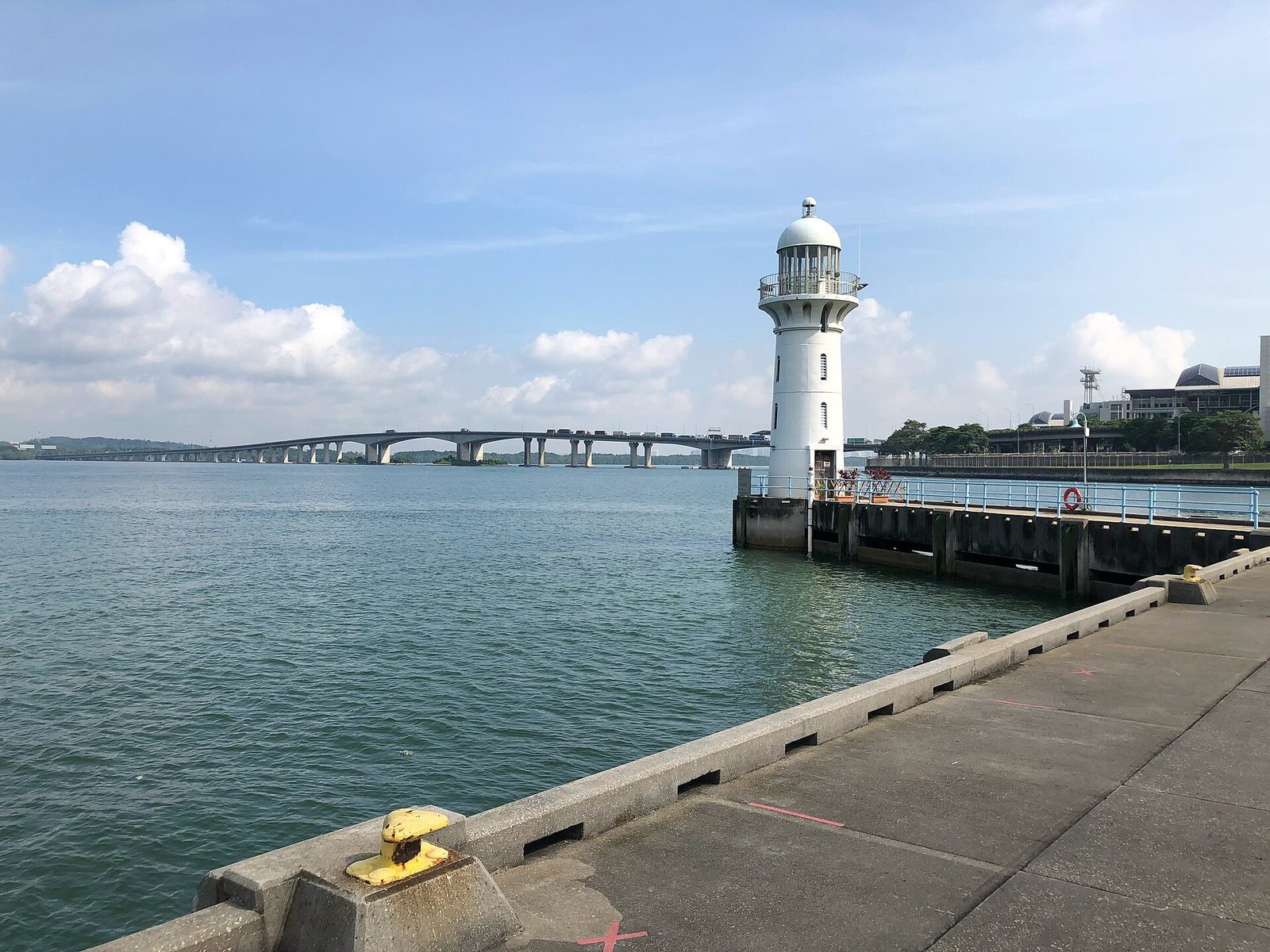 Le phare blanc de Raffles Marina au bord de l'eau, avec le long pont du Second Link vers la Malaisie en arrière-plan