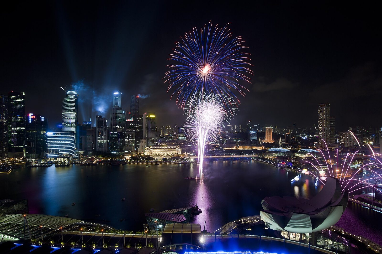 Feux d'artifice au-dessus de Marina Bay, la nuit, avec la tribune de la plateforme flottante et les tours du quartier d'affaires illuminées