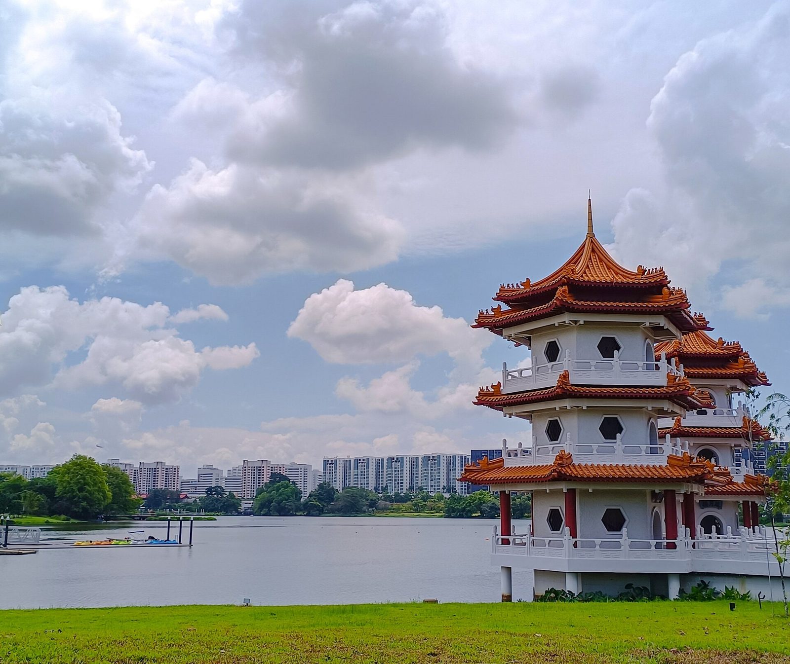 Une pagode chinoise blanche à toits orange superposés au bord du lac Jurong, sous un ciel nuageux