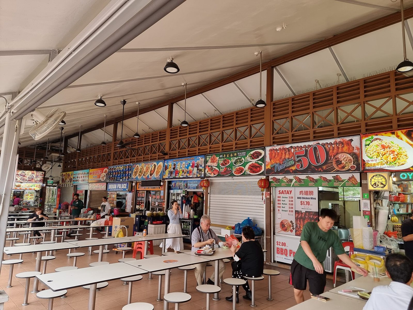 Les stands et les tables du Newton Food Centre, un hawker centre de Singapour, avec des clients attablés