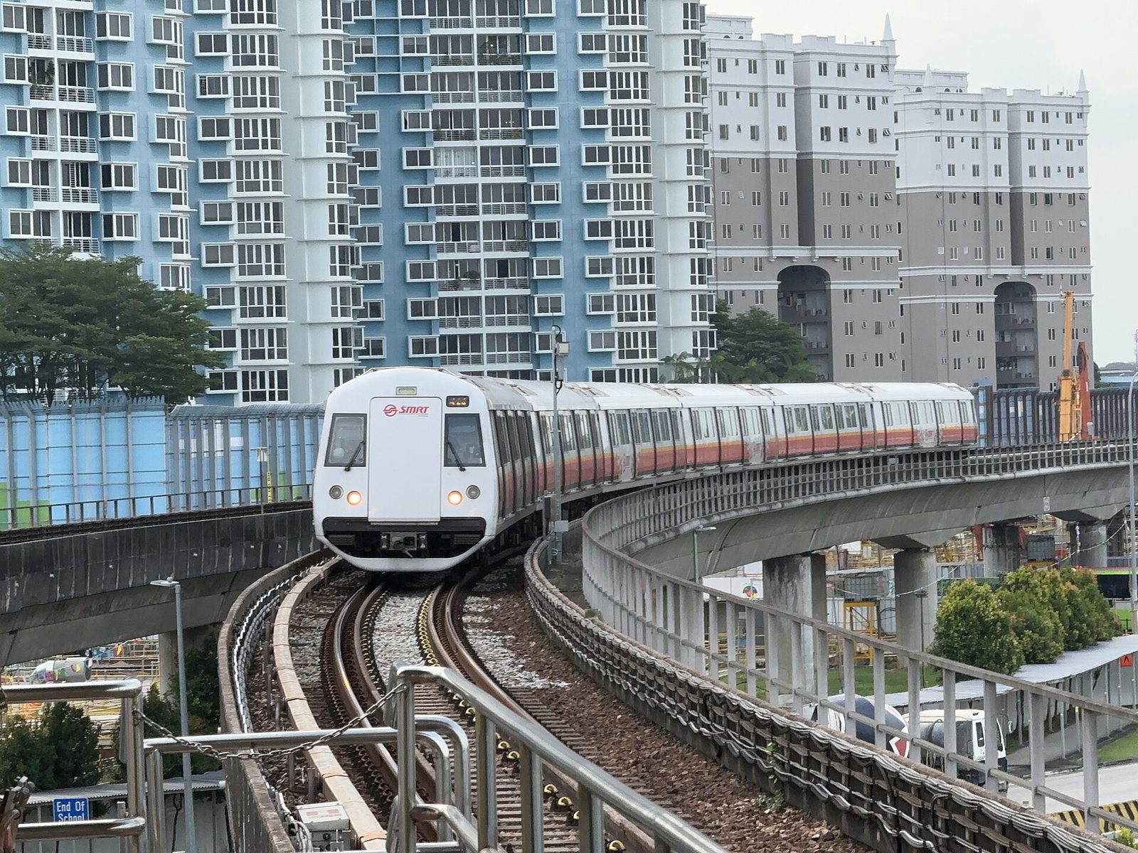 Une rame blanche du métro MRT de la North-South Line dans une courbe sur viaduc, entre des tours de logements HDB, à Yio Chu Kang