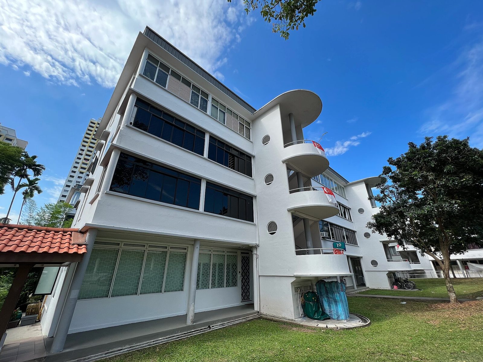 Un immeuble blanc aux balcons arrondis du Singapore Improvement Trust, entouré de pelouse et d'arbres, à Tiong Bahru Road