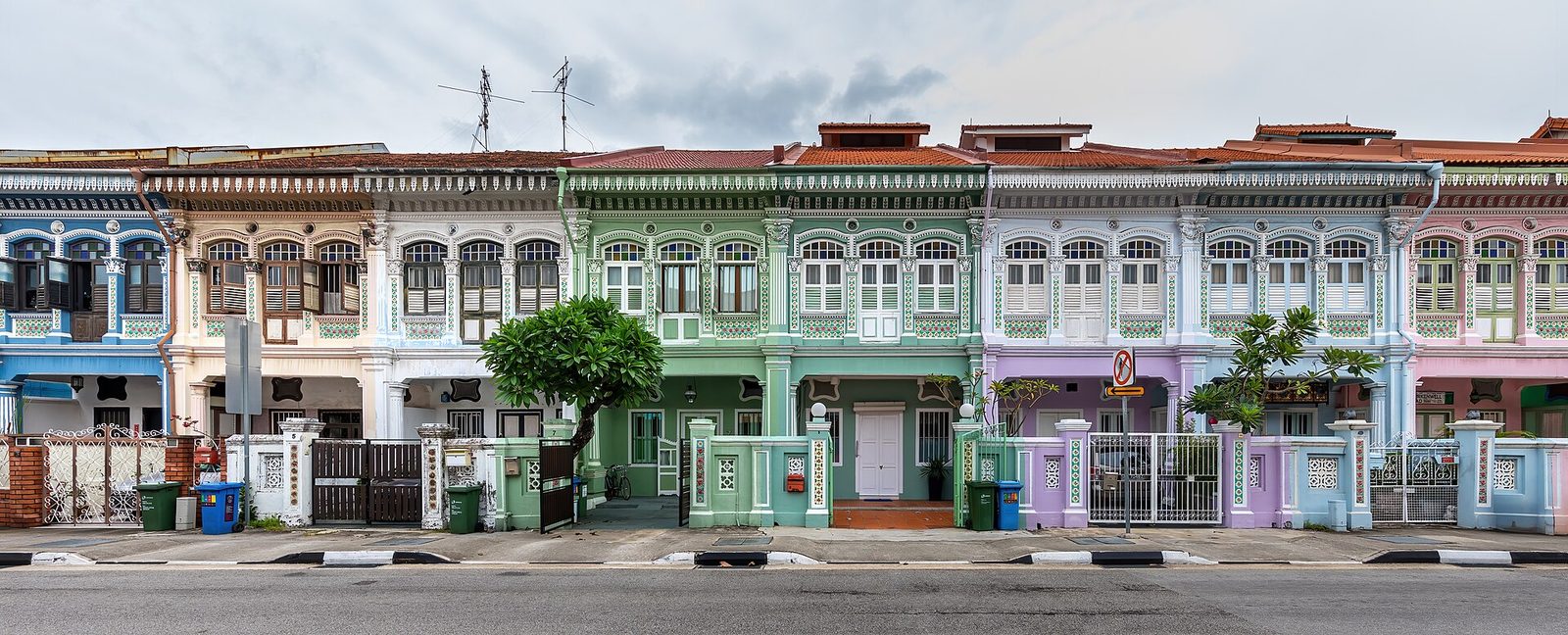Rangée de maisons mitoyennes colorées, vertes, blanches et mauves, avec des façades ornées de style peranakan à Koon Seng Road