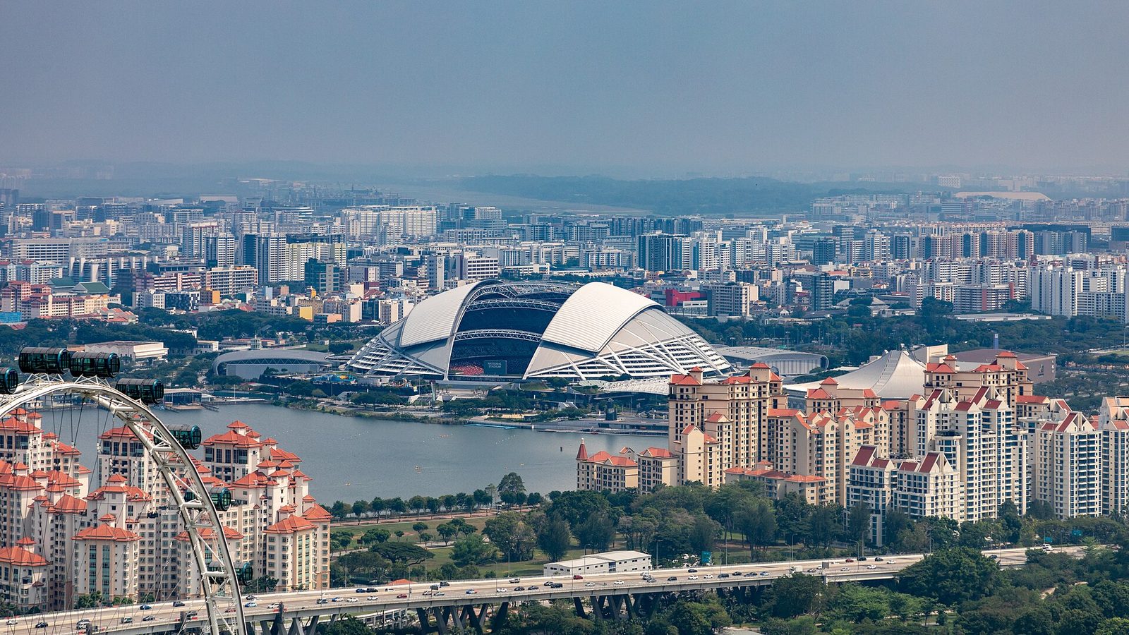 Vue aérienne du National Stadium de Singapour et de son toit en dôme, au bord du bassin de Kallang, entouré d'immeubles