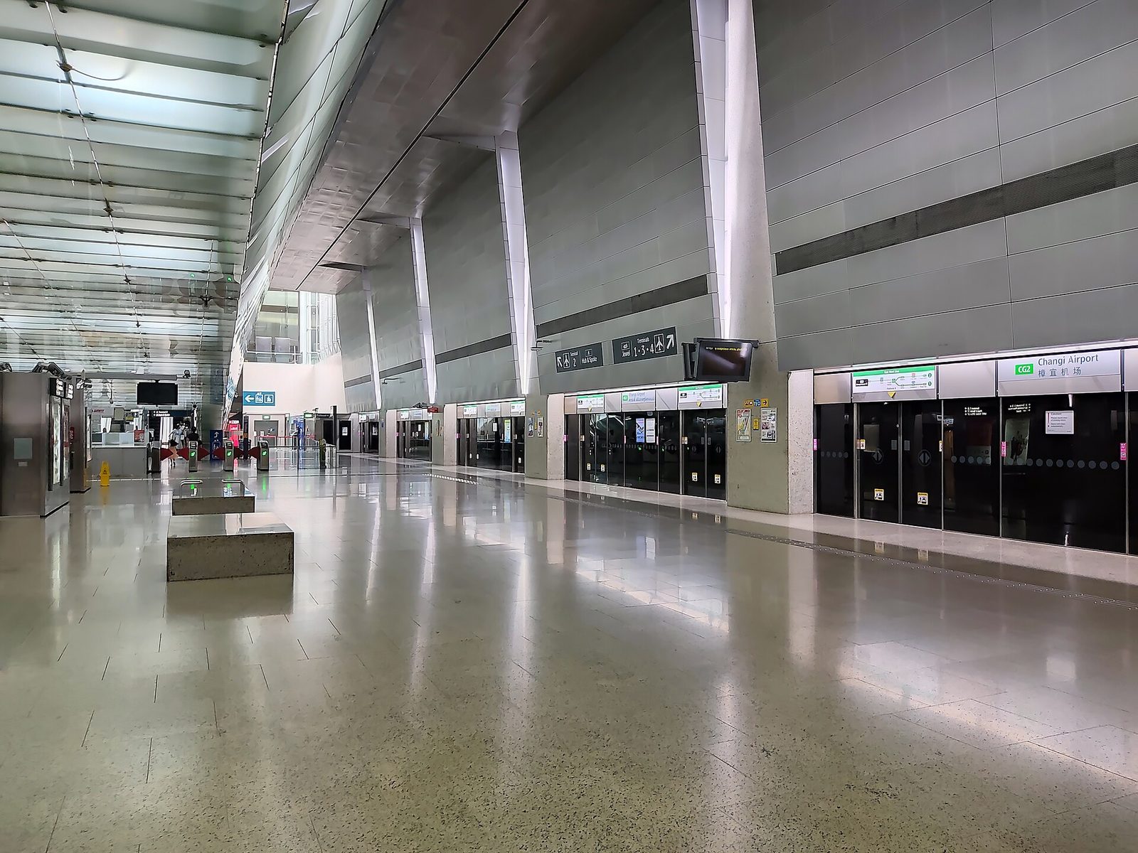 Le vaste quai de la station de métro Changi Airport, avec son haut plafond incliné et ses portes palières