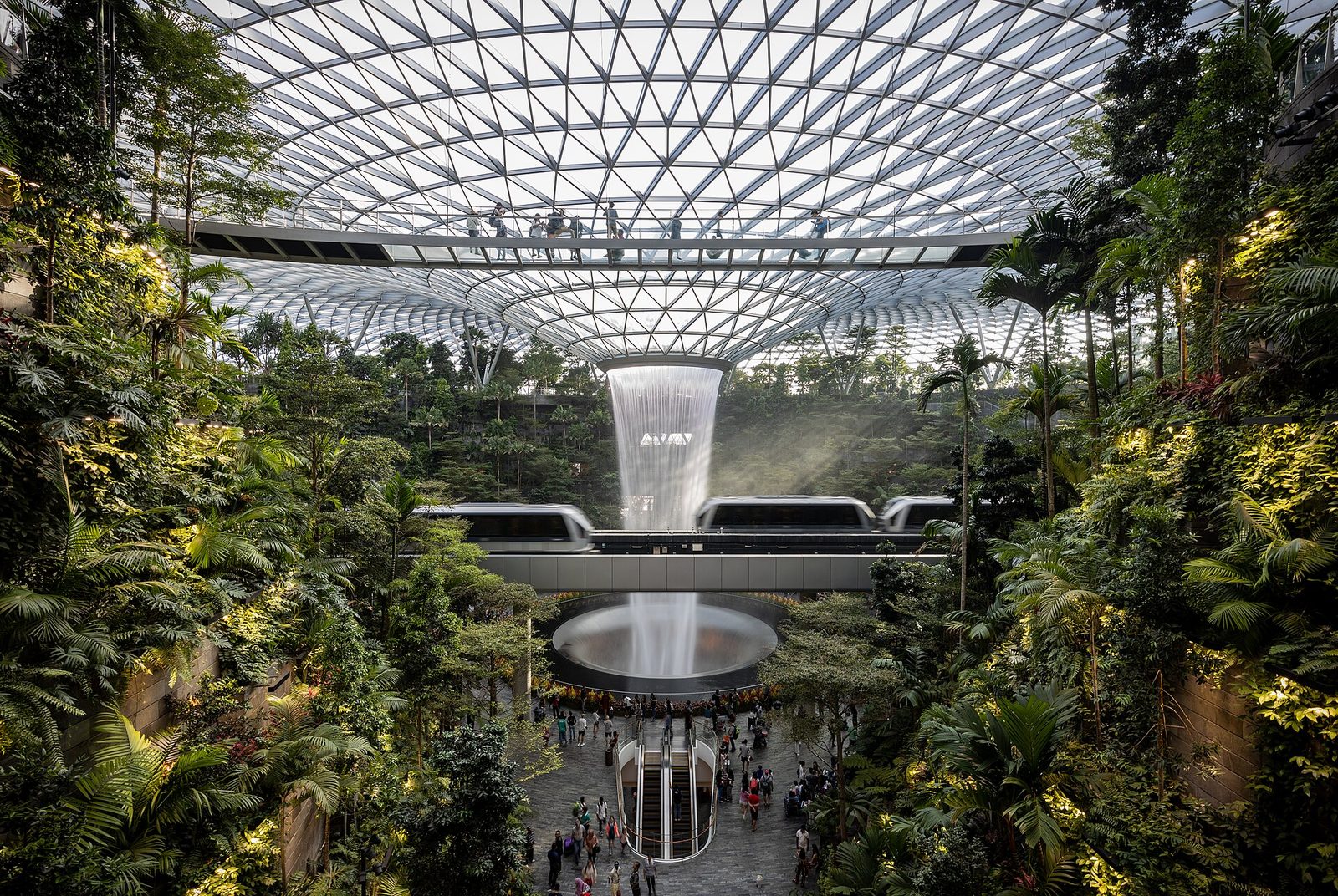 La cascade intérieure du Rain Vortex tombant du dôme de verre de Jewel Changi Airport, entourée d'une forêt tropicale sur plusieurs étages