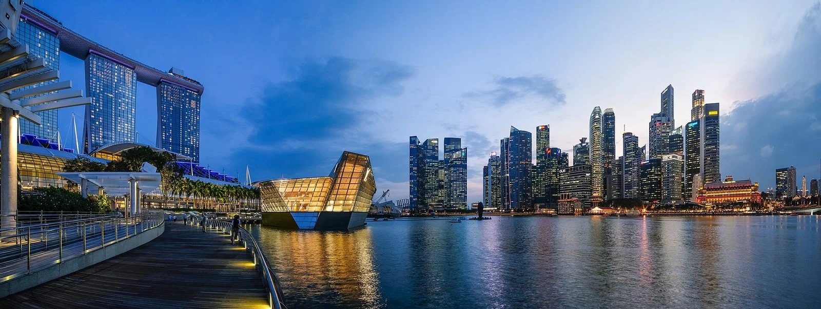 Panorama de Marina Bay au crépuscule, avec les tours de Marina Bay Sands à gauche et les gratte-ciel illuminés du quartier d'affaires à droite