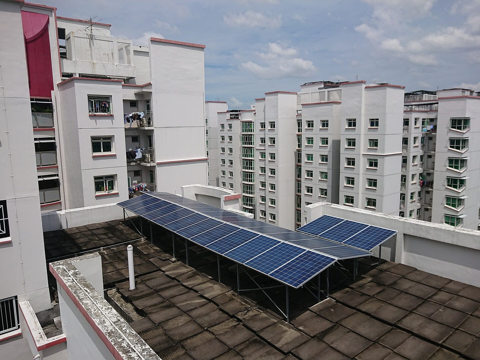 Panneaux solaires installés sur le toit d'un immeuble de logements publics HDB à Punggol, entourés d'autres tours blanches